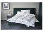 Une couette en duvet Fjodur blanche sur un lit vert foncé.
