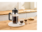 Cafetière à piston, deux tasses de café et des biscuits sur une table en bois dans la cuisine.