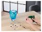 Une personne décore un vase turquoise avec des pierres de verre à l'aide d'un pistolet à colle.