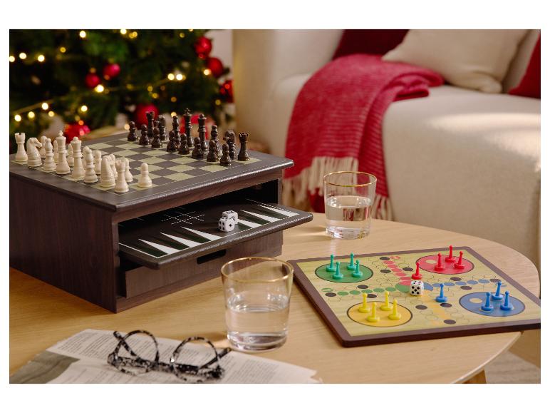 Jeux de société, dont les échecs, le backgammon et le Ludo, sur une table basse près d'un sapin de Noël.