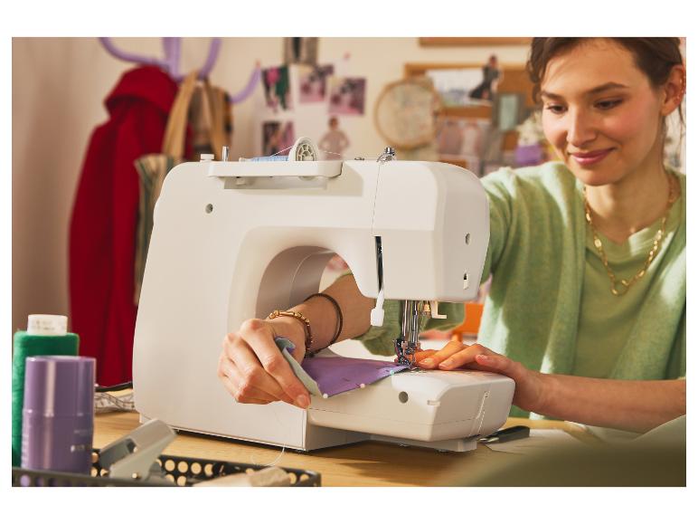Une femme coud sur une machine à coudre blanche.