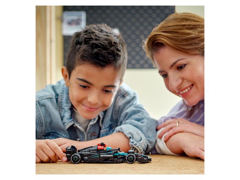 Un enfant et sa mère jouent avec une maquette de voiture de course LEGO Mercedes-AMG Petronas Formula One™ Team.