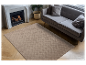 Tapis beige texturé posé sur un parquet clair devant un canapé gris.