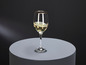 Un verre de vin blanc avec une bordure dorée sur un fond rond gris.