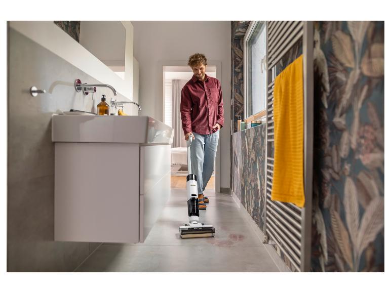 Homme nettoyant le sol de la salle de bain avec un nettoyeur de sol sans fil.