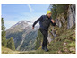 Homme marchant sur un sentier de montagne avec des chaussures de randonnée et un gilet.
