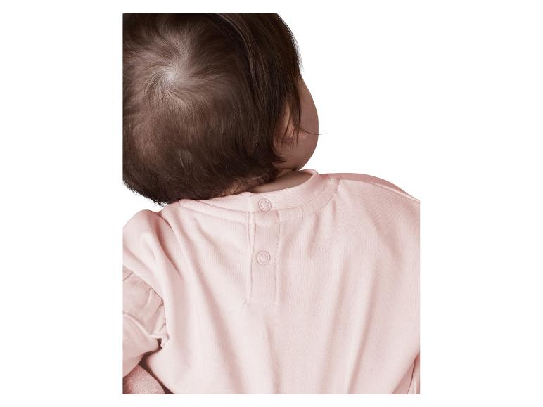 Arrière de la tête de bébé et chemise rose à boutons-pression.