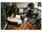 Homme lisant un livre sur un balcon avec mobilier d'extérieur, plantes et guirlandes lumineuses.