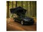 Voiture avec tente de toit et échelle dans une forêt.
