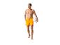 Homme en maillot de bain orange tenant un ballon de volley.