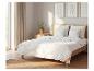 Chambre avec un lit doté d'une literie matelassée blanche, d'oreillers et d'une tête de lit en bois.