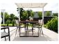 Ensemble de salle à manger de jardin avec table et chaises sous une pergola, entouré de verdure.