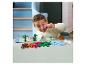 Un enfant joue avec des briques LEGO DUPLO dinosaures et volcan sur une table.