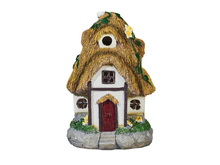 Une petite maison avec un toit de chaume et une porte rouge.