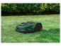 Tondeuse robot verte Parkside sur une pelouse devant des buissons.