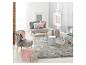 Chambre d'enfant avec mobilier gris et rose, tapis et coussins.