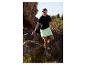 Femme en t-shirt noir et jupe-short verte marchant dans un paysage rocheux.