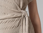Gros plan sur une robe beige cintrée avec un nœud.
