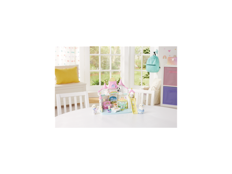 Ensemble de jeu de crèche avec château rose, animaux jouets et accessoires sur une table blanche.