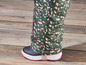 Gros plan sur un pantalon vert à imprimé rose et des bottes de neige noires.