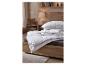 Literie et oreillers blancs sur un lit dans une chambre confortable.