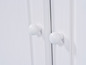 Deux boutons blancs sur une porte de placard en bois blanc.