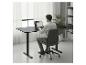 Homme travaillant sur un ordinateur portable à un bureau de bureau réglable noir dans un espace moderne.