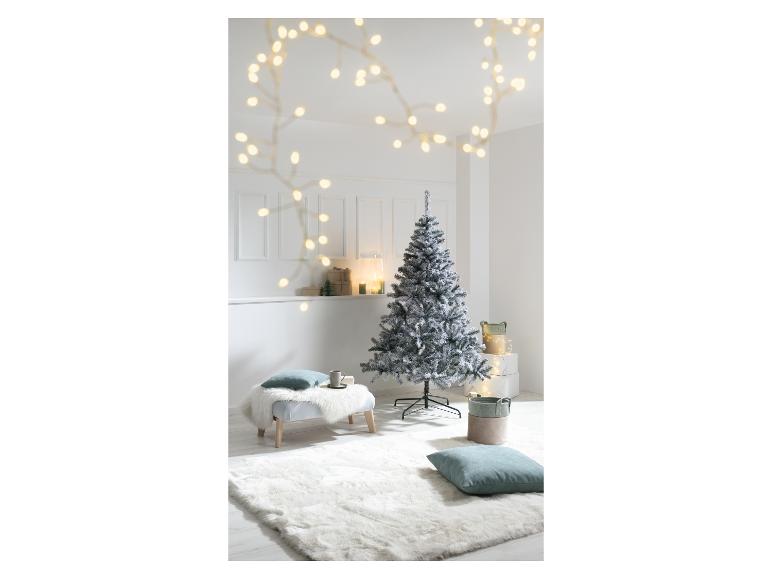 Un sapin de Noël floqué dans une pièce blanche avec des guirlandes lumineuses et des cadeaux.