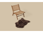 Chaise en bois avec assise et dossier tressés, à côté d'un tapis en fausse fourrure marron.
