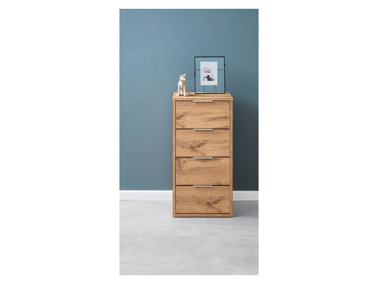 Une commode en bois avec quatre tiroirs contre un mur bleu.
