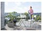 Femme nettoyant des meubles de balcon avec un nettoyeur haute pression sur un balcon avec vue.