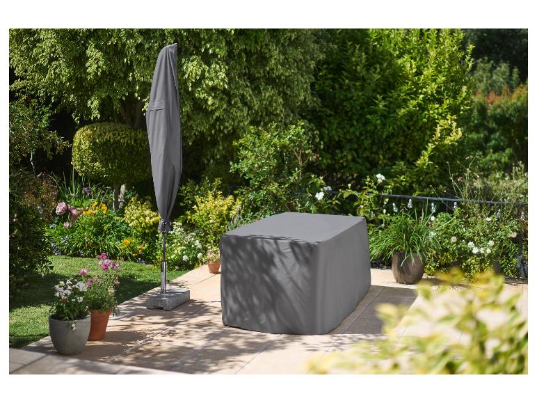 Housses de mobilier de jardin et parasol dans un jardin fleuri.