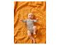 Bébé heureux en body gris allongé sur une couverture orange gaufrée.