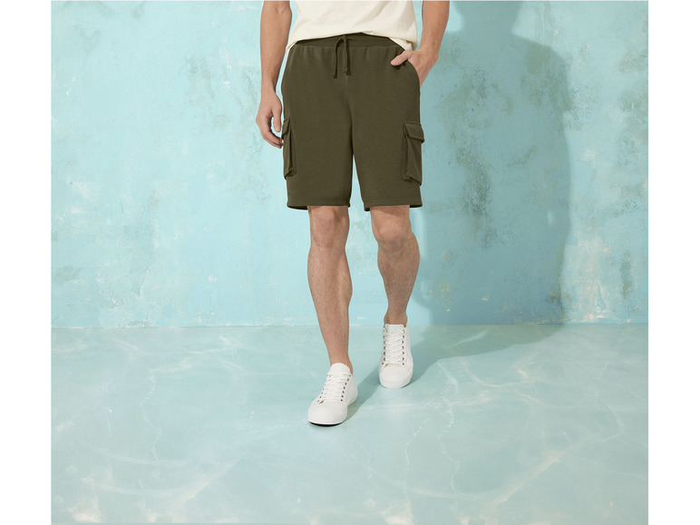 Un homme portant un short cargo vert et des baskets blanches.