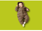 Bébé en combinaison matelassée marron à capuche, allongé sur fond vert.