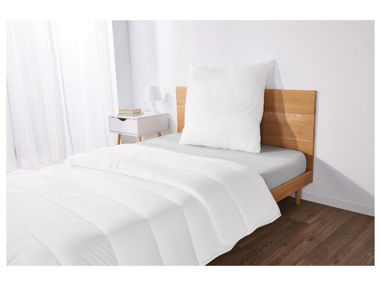 Une couette et un oreiller blancs sur un cadre de lit en bois.