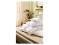 Une couette et des oreillers blancs empilés sur un lit.