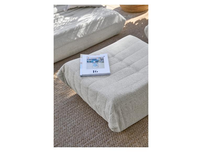 Poufs rembourrés gris clair sur un tapis tissé, avec un magazine dessus.