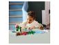 Enfant jouant avec des dinosaures et un volcan LEGO Duplo sur une table.