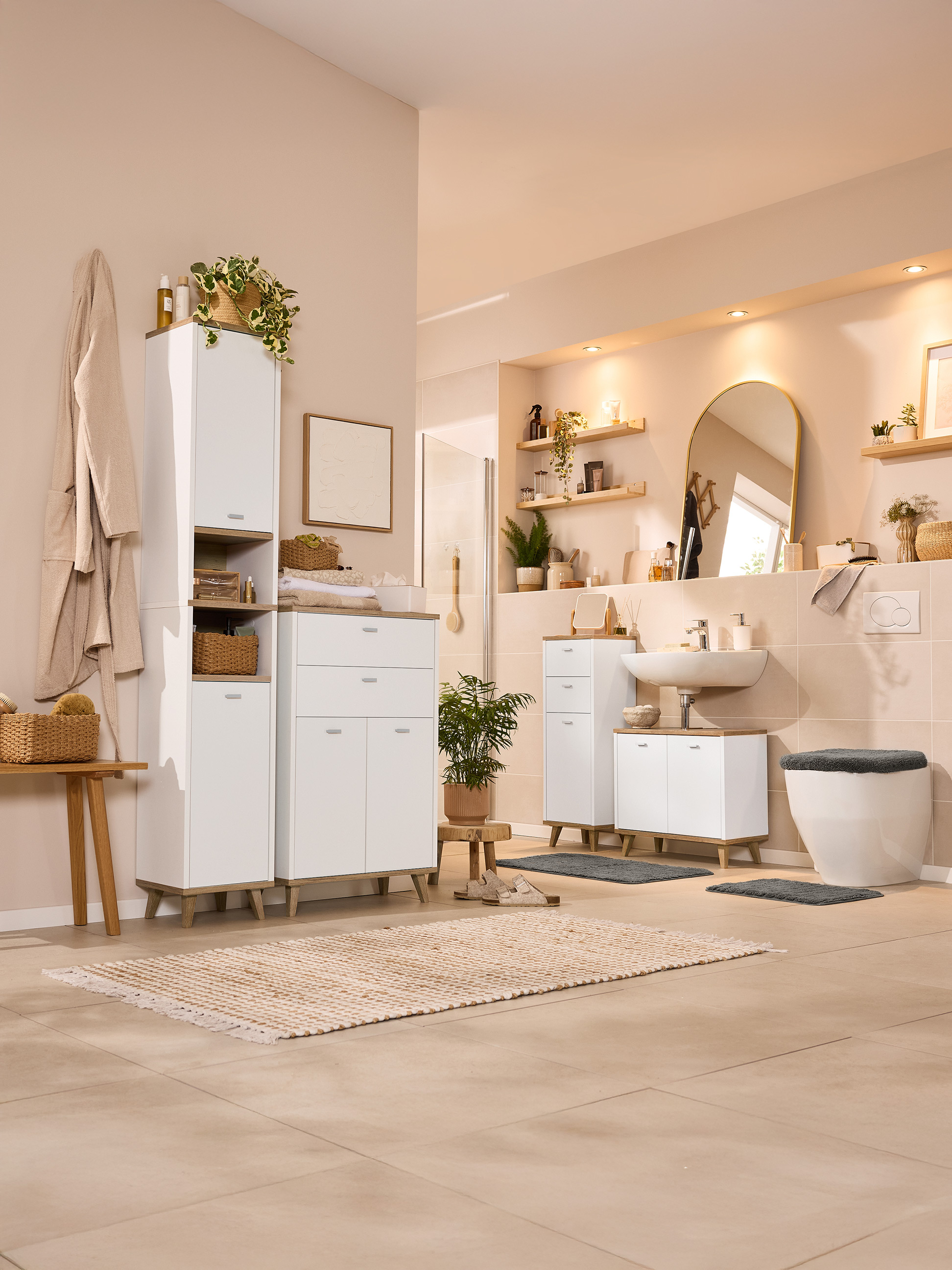 Salle de bain lumineuse avec meubles blancs, accents boisés et plantes.