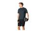 Homme en t-shirt de sport, short et gants, tenant un casque de vélo.