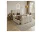 Chambre avec lit rembourré beige avec tiroirs, table de chevet et décoration.