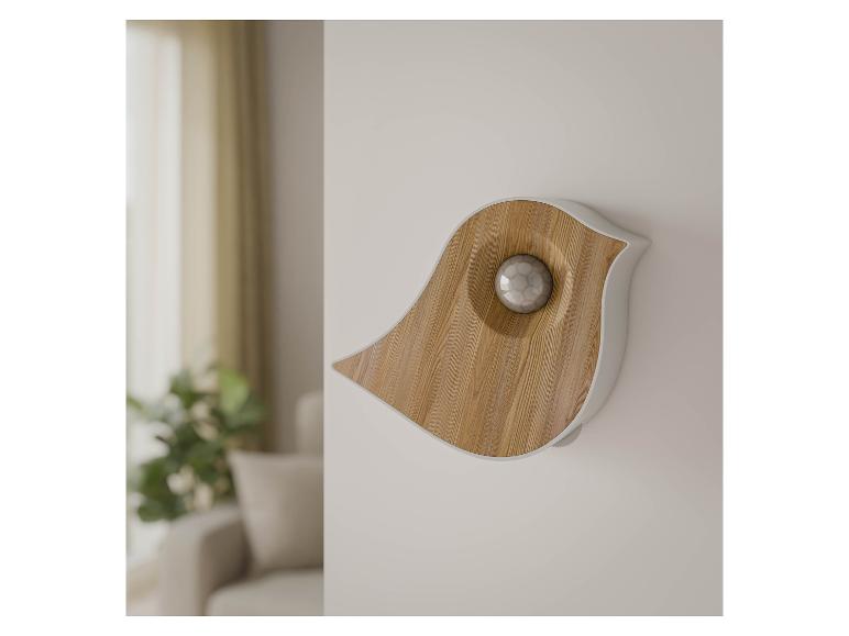 Appareil mural en forme d'oiseau en bois clair et blanc, avec une sphère au centre.