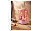 Conteneur rose pour nettoyer les pinceaux de maquillage avec des pinceaux dans l'eau, sur un comptoir en bois.