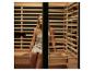 Femme se relaxant dans un sauna en bois, les yeux fermés.