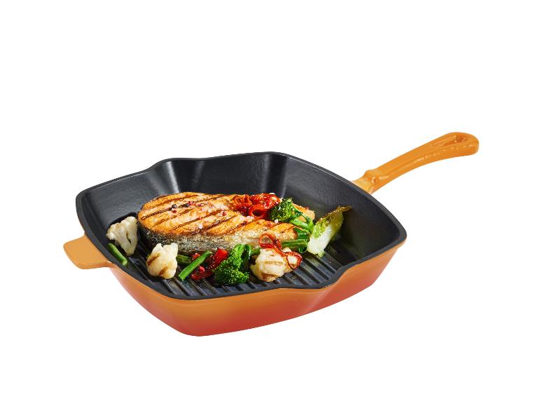 Une poêle carrée orange avec un steak de saumon grillé et des légumes.