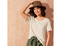 Une femme porte un t-shirt blanc, un pantalon vert et un chapeau de paille.