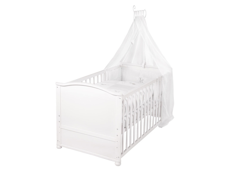 Un lit bébé blanc avec un ciel de lit.