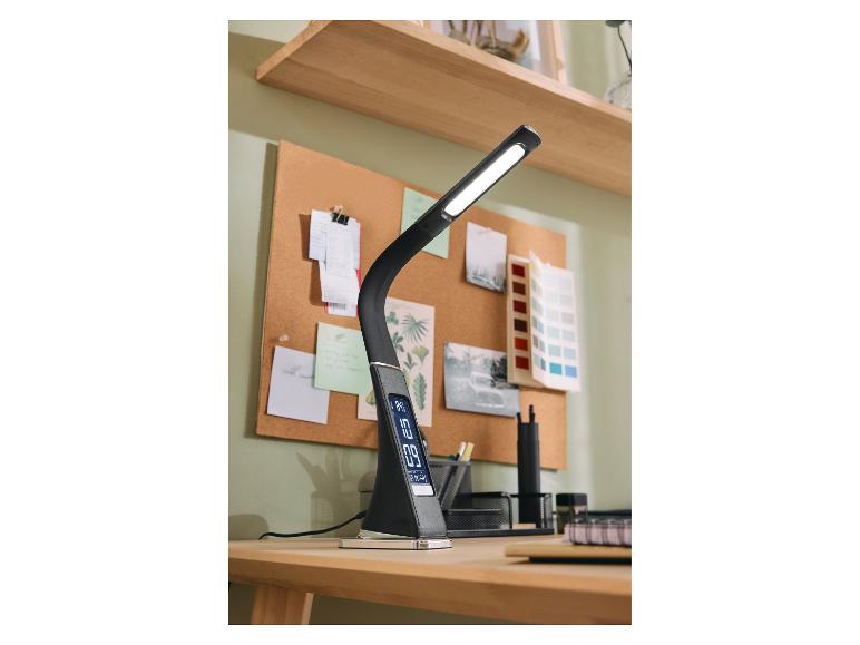 Lampe de bureau LED noire avec affichage numérique sur un bureau en bois avec tableau en liège.