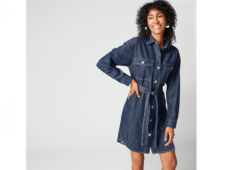Une femme porte une robe en jean bleu avec une ceinture.